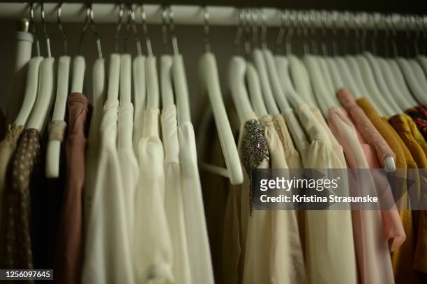 blouses arranged by color, hanging on a coathangers on a clothing rack - silk garment stock pictures, royalty-free photos & images