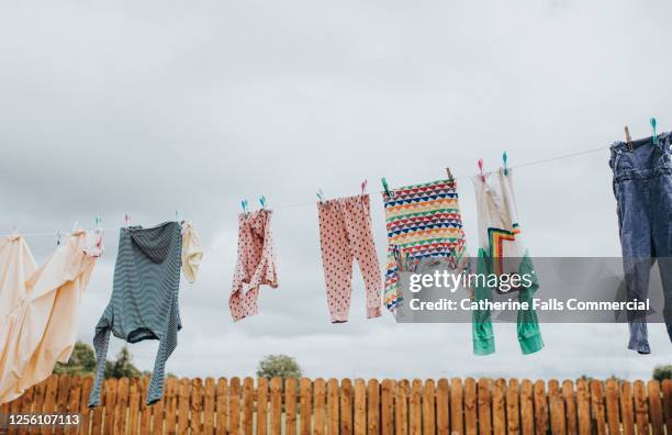 washing hanging on a washing line in a paved back yard - ropa tendida fotografías e imágenes de stock