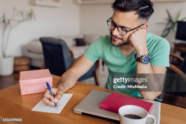 young man writing a letter and preparing a gift box for someone - man writing a letter stock pictures, royalty-free photos & images