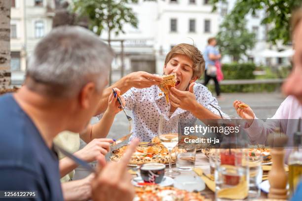 vrienden die pizza in het restaurant in openlucht eten - pizzeria stockfoto's en -beelden