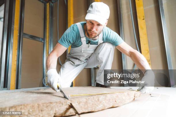 bouwvakker die minerale rotswol snijdt - isolatiemateriaal stockfoto's en -beelden