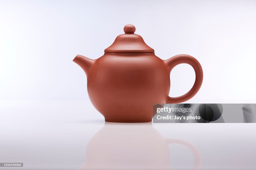 Brown clay teapot on white white background, studio shot.