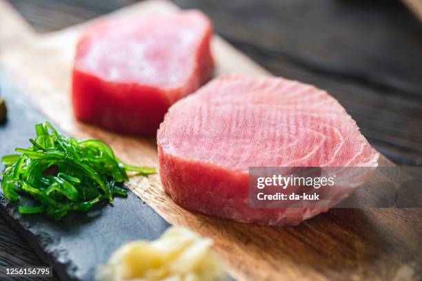 ruwe tonijnsteak met ingrediënten op een snijplank - raw fish stockfoto's en -beelden