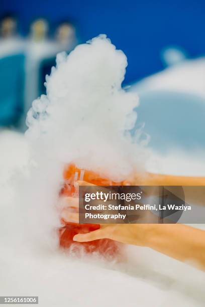 child's hands holding bottle with edible smokey liquid nitrogen - nitro stock-fotos und bilder