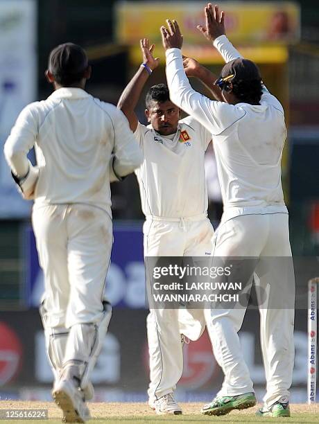 Sri Lankan spinner Rangana Herath celebrates with his teammates after he dismissed unseen Australian batsman Ricky Ponting during the fourth day of...