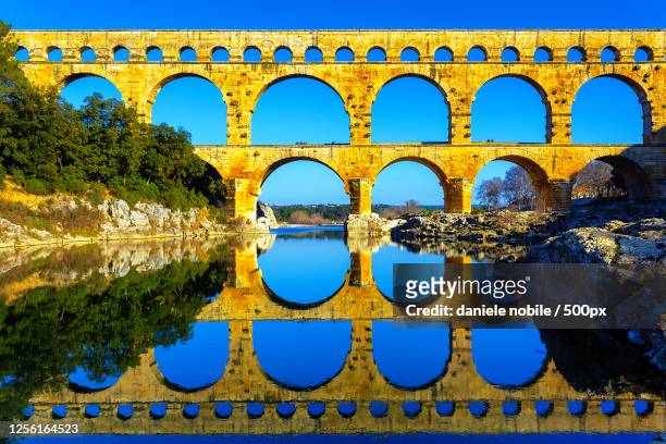 pont du gard reflecting in river, castillon-du-gard, france - pont du gard ストックフォトと画像