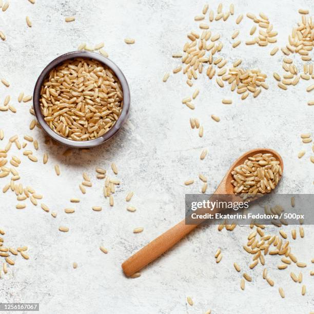 brown rice in wooden bowl with spoon - naturreis stock-fotos und bilder