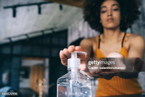 mulher afro aplicando desinfetante para as mãos, durante covid-19 - hand sanitiser - fotografias e filmes do acervo