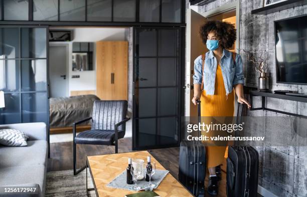 schöne afro-frau mit schützender gesichtsmaske im hotelzimmer ankommen - gast stock-fotos und bilder