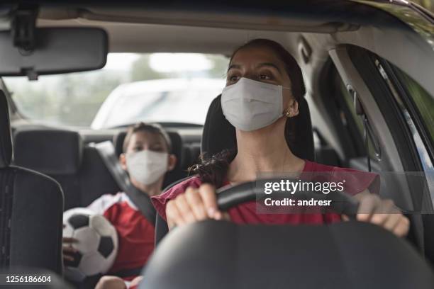 madre conduciendo a su hijo a la práctica de fútbol usando una máscara facial para evitar una enfermedad infecciosa - football face mask fotografías e imágenes de stock