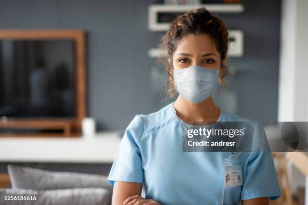 nurse using a facemask while making a house call during the covid-19 pandemic - n95 face mask stock pictures, royalty-free photos & images
