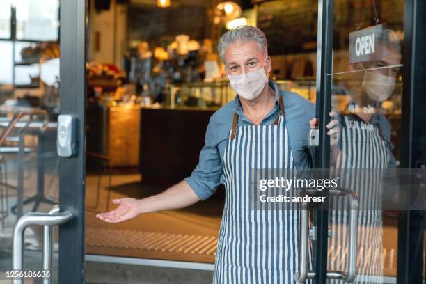 business owner wearing a facemask and reopening his cafe after the quarantine - reopening sign stock pictures, royalty-free photos & images