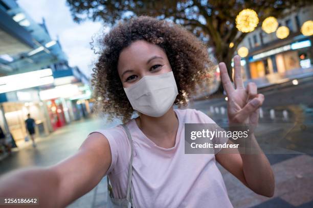 woman wearing a facemask and taking a selfie on the street - aussie flu stock pictures, royalty-free photos & images