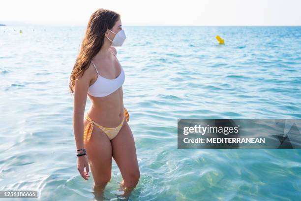 tourist bikini mädchen mit gesichtsmaske in pandemie am strand - swimsuit models girls stock-fotos und bilder