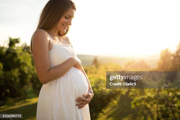 junge frau erwartet ein baby. - grünes kleid stock-fotos und bilder