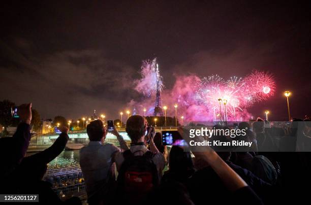 Parisians watch the the annual Firework display over the Eiffel Tower to celebrate Bastille Day from the banks of the River Seine on July 14, 2020 in...