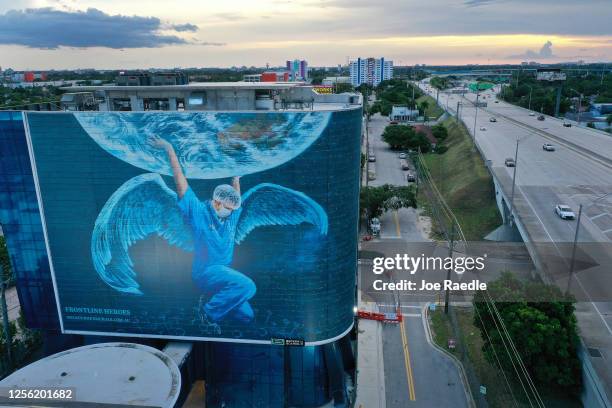 In this aerial photo from a drone, a billboard depicting a medical worker holding up the world is seen on the side of a building as the county deals...