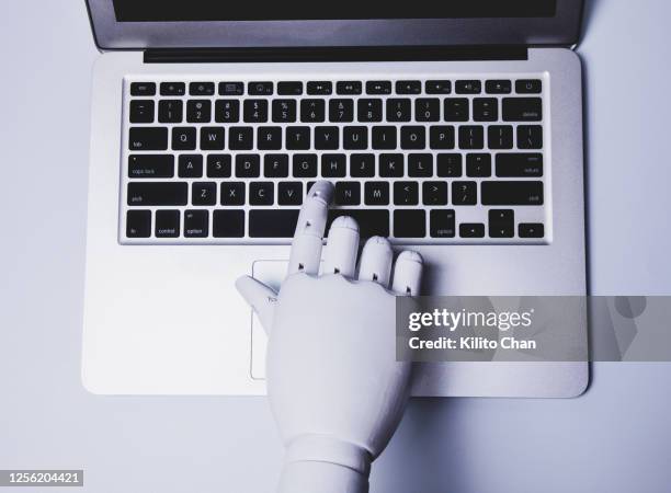 robotic hand using laptop (concept of ai replacing white collar worker) - raised finger stock-fotos und bilder