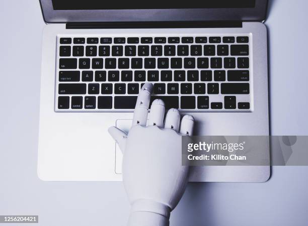 robotic hand using laptop (concept of ai replacing white collar worker) - robot hand stock pictures, royalty-free photos & images
