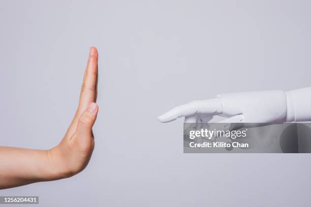 human hand raised rejecting robotic hand (concepts of human rejecting ai) - weigeren stockfoto's en -beelden