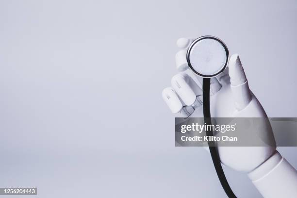 robotic hand holding stethoscope (concepts of ai medical care) - roboter hand stock-fotos und bilder