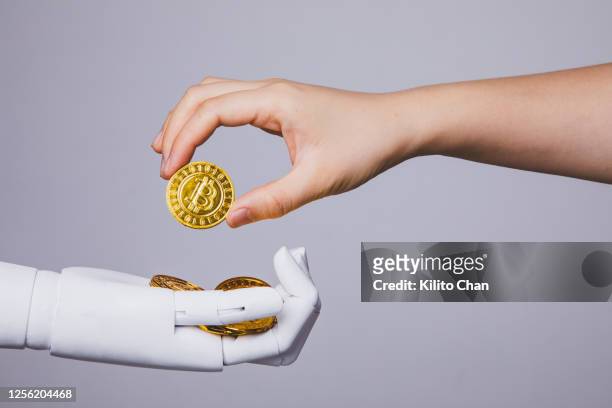 human hand taking bitcoin from robotic hand - bitcoin stock pictures, royalty-free photos & images