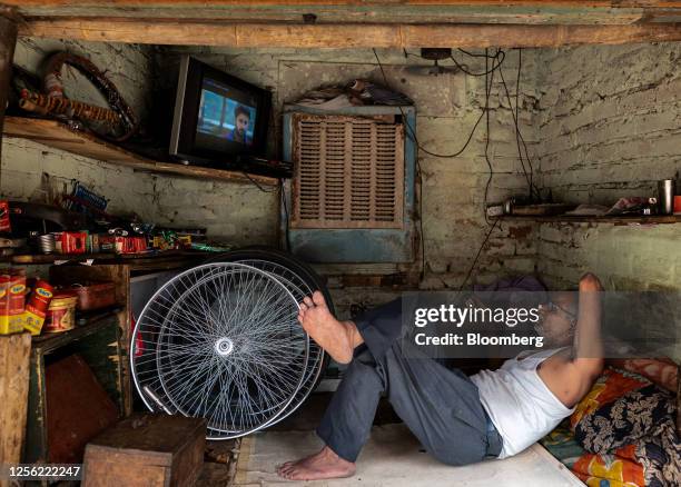 Vendor watches television while resting inside a bicycle repair shop in New Delhi, India, on Friday, May 19, 2023. The extreme heat that baked parts...