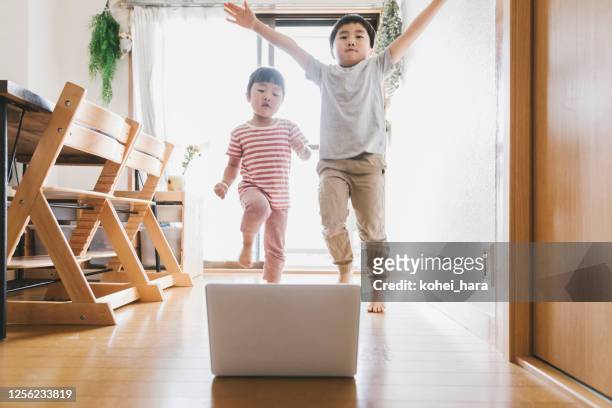 Siblings watching laptop and dancing at home