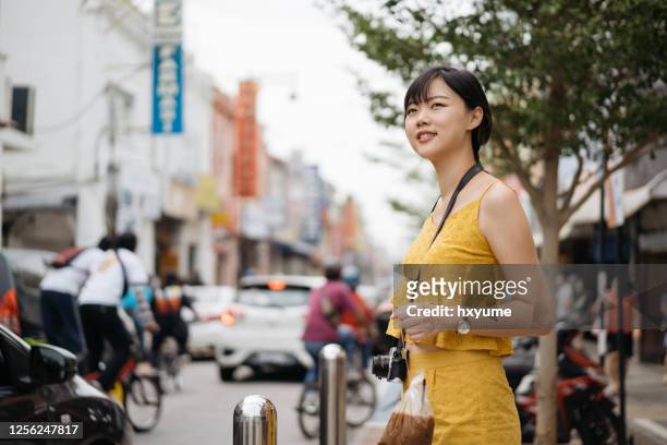 young asian female tourist holding malaysian style take out ice coffee in plastic bag with drinking straw - penang state stock pictures, royalty-free photos & images
