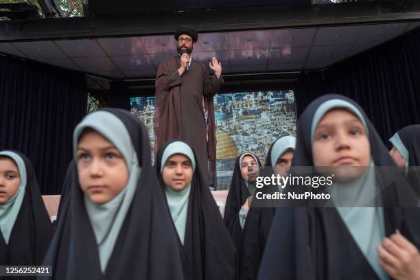 An Iranian cleric speaks while standing behind veiled schoolgirls at the Imam Khomeini grand mosque in downtown Tehran, during a ceremony marking...