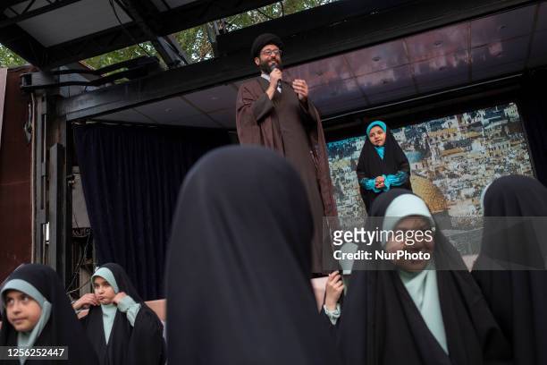 An Iranian cleric speaks while standing behind veiled schoolgirls at the Imam Khomeini grand mosque in downtown Tehran, during a ceremony marking...