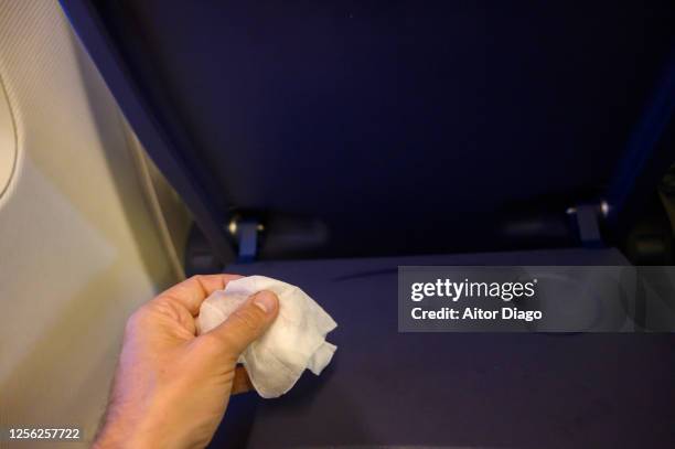 man's hand cleaning the airplane tray with a tissue - airplane tray table stock pictures, royalty-free photos & images