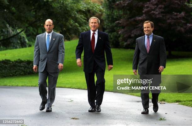 President George W. Bush walks with White House Press Secretary Ari Fleischer and Deputy Assistant to the President Scott McClellan on the South Lawn...