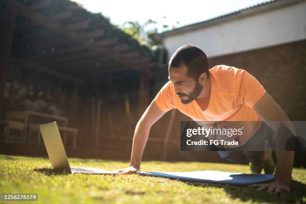 man doing push-ups during a virtual exercise class - fitness instructor at home stock pictures, royalty-free photos & images