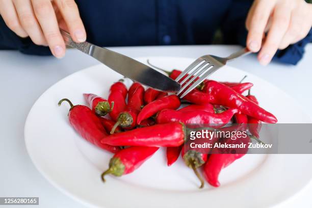 girl hands with fork and knife, woman cuts red hot spicy cayenne pepper on a white plate. proper nutrition, vegetarian food, healthy lifestyle diet concept. - female eating chili bildbanksfoton och bilder
