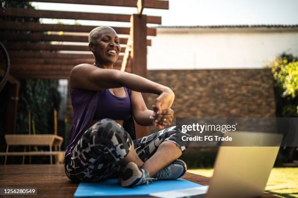 woman doing a virtual exercise class, stretching her arms - virtual showing stock pictures, royalty-free photos & images