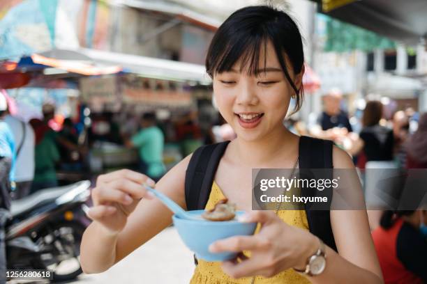 年輕的亞洲��女性遊客享受剃冰甜點在街頭 - george town penang 個照片及圖片檔