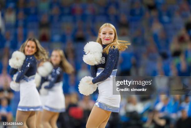 cheerleader performing on court - cheerleaders stock pictures, royalty-free photos & images