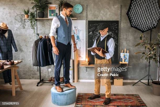 professional tailor taking measures for a suit - tailor suit stock pictures, royalty-free photos & images