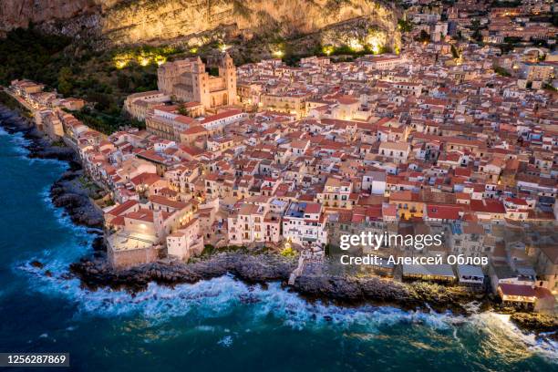 aerial view of the rocky coast and the houses of cefalu from the sea in windy and stormy weather. big waves beat against stones. streets with the city lights. italy, tyrrhenian seasicily, italy - palermo sicily fotografías e imágenes de stock