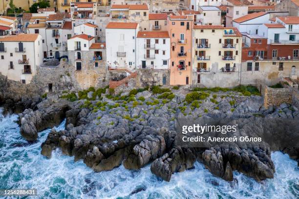 aerial view of the rocky coast and the houses of cefalu from the sea in windy and stormy weather. big waves beat against stones. sicily, italy - abruzzi foto e immagini stock