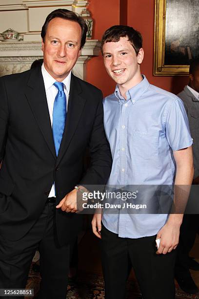 Callum Fairhurst poses with David Cameron after presenting him with a bracelet to raise money for his friend who has a brain tumor at a reception...