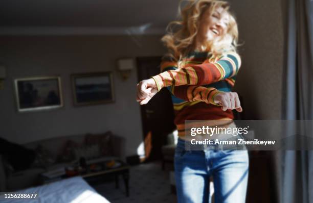 happy woman with long hair jumping and dancing at home - long jump photos et images de collection