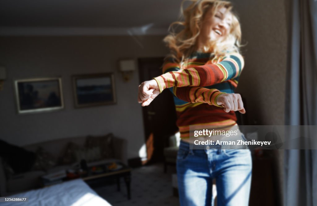 Happy woman with long hair jumping and dancing at home