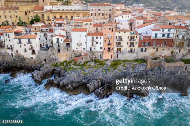 aerial view of the rocky coast and the houses of cefalu from the sea in windy and stormy weather. big waves beat against stones. sicily, italy - tyrrhenisches meer stock-fotos und bilder