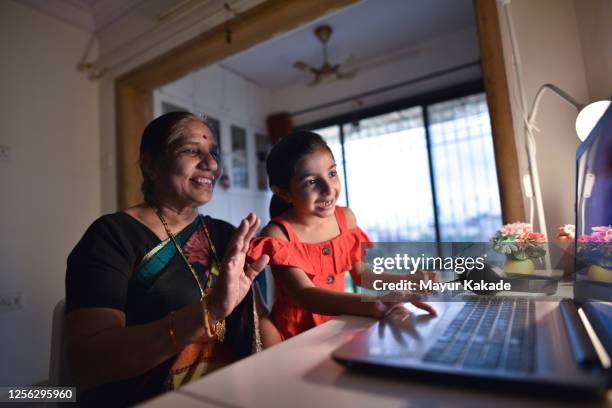 grandmother and granddaughter video conferencing using laptop - indian grandparents stock pictures, royalty-free photos & images