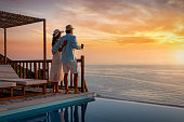 A romantic couple on summer vacation enjos the sunset over the mediterranean sea by the pool