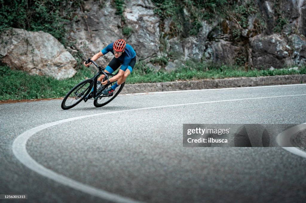 Ciclista in bicicletta sulla curva della strada asfaltata