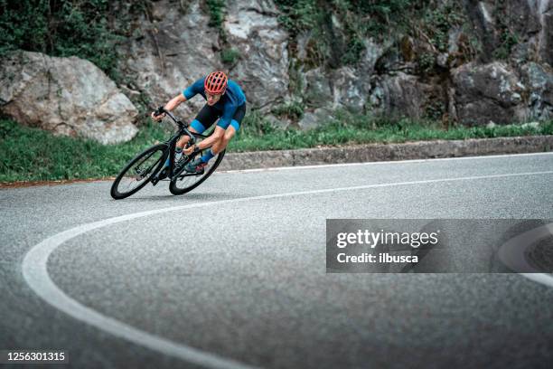 de rennende fietser van de fiets op de kromme van de asfaltweg - biking athletic stockfoto's en -beelden
