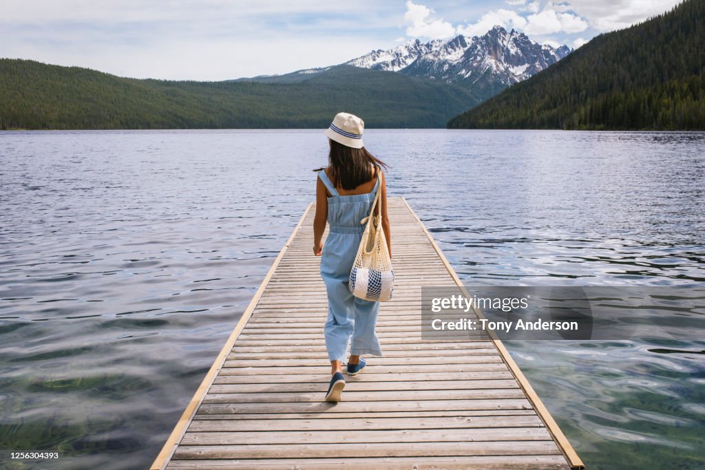 Young woman walking on dock at mountain lake